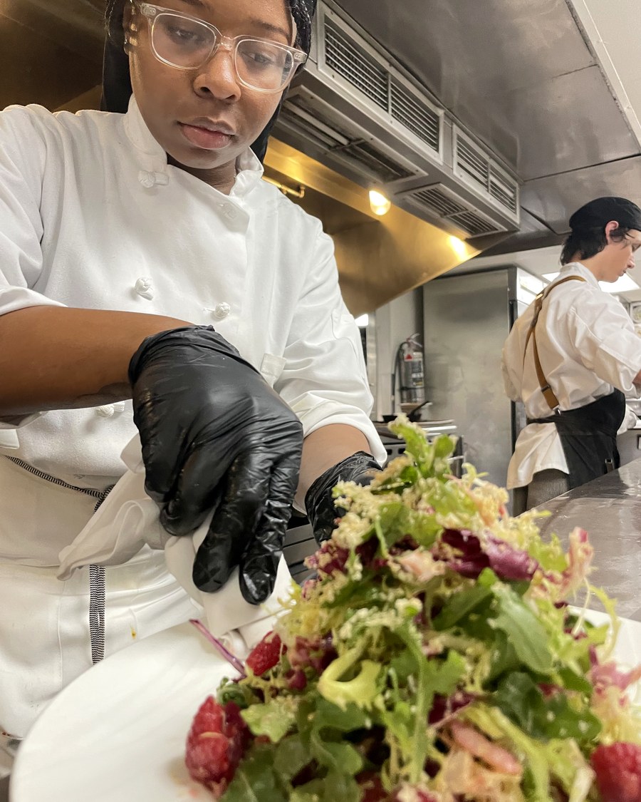 Chef Aniya dressing a salad in the kitchen