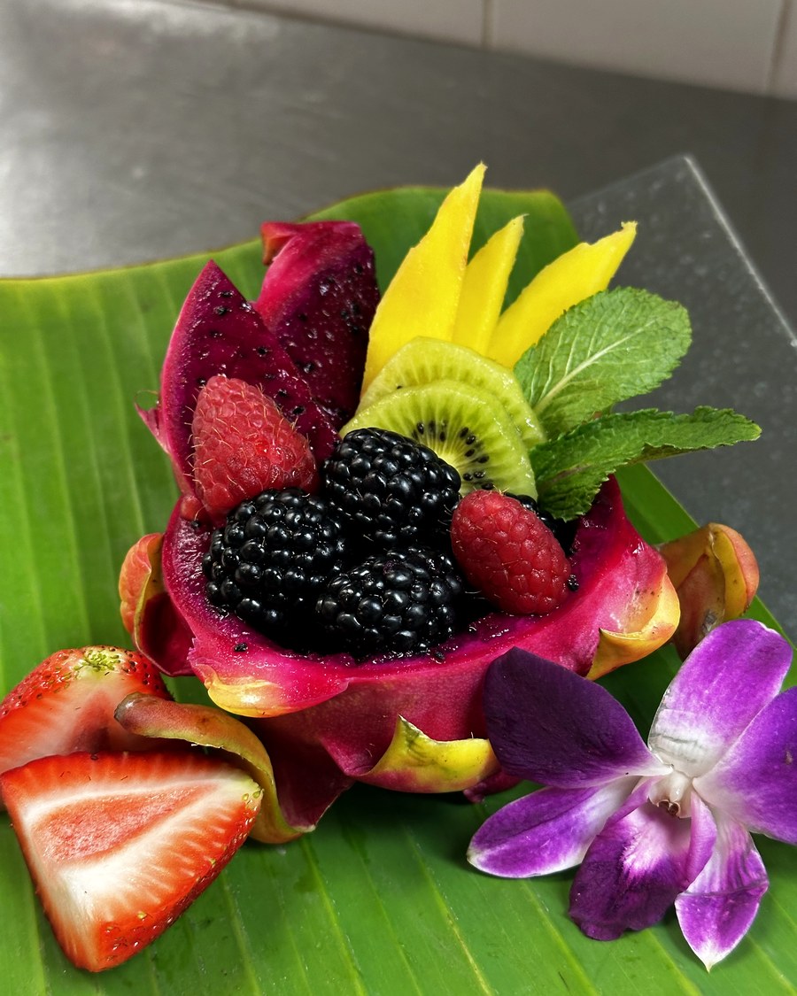 Fruit display with dragon fruit, berries, and flowers