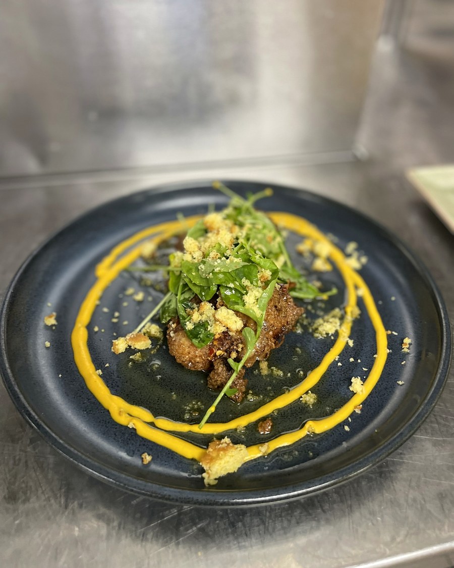 Plated entree with greens and yellow sauce